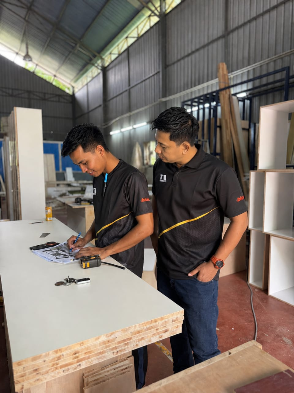 Pasukan menyemak pelan rekaan kabinet di kilang